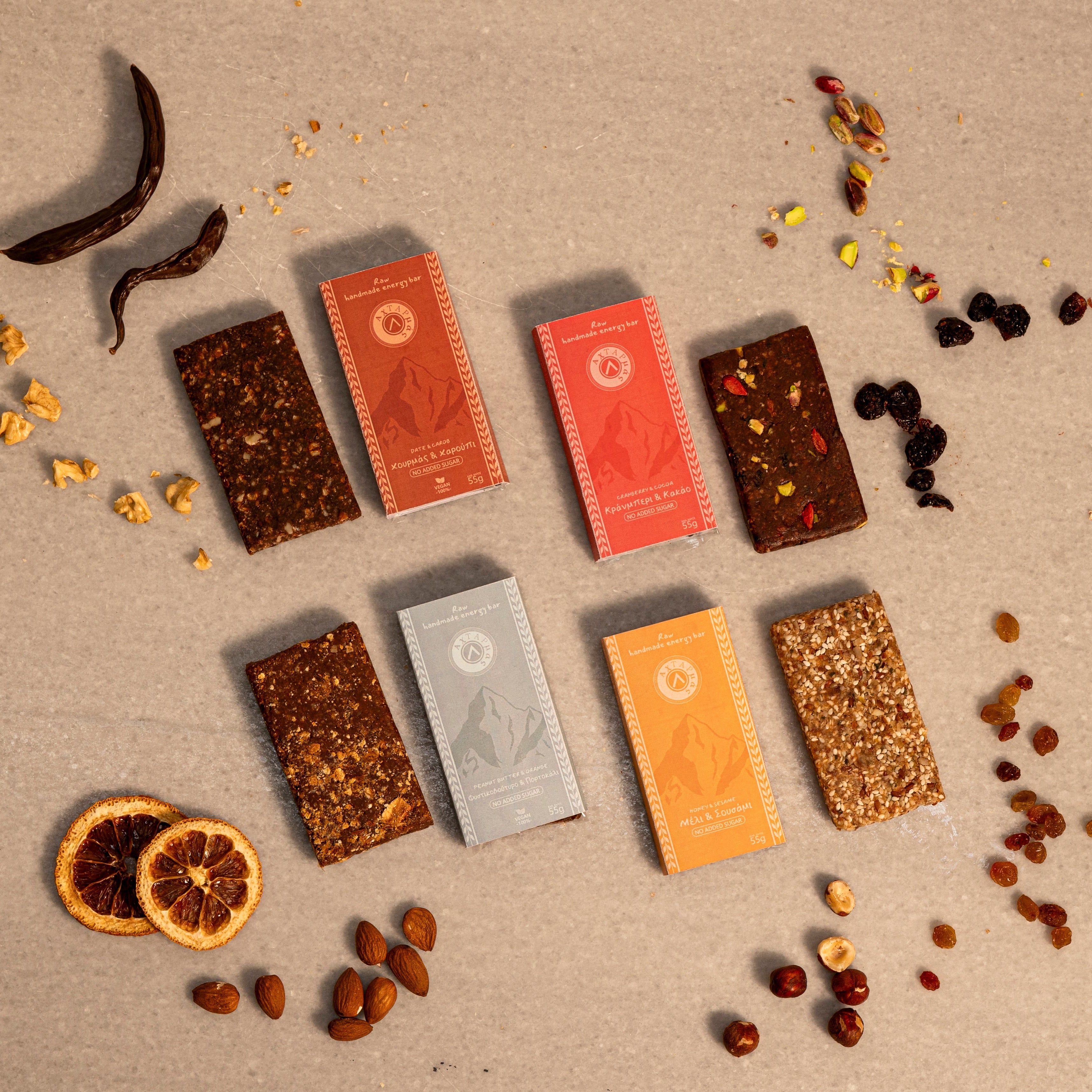 Assorted raw energy bars on a textured surface with dried fruits and nuts.
